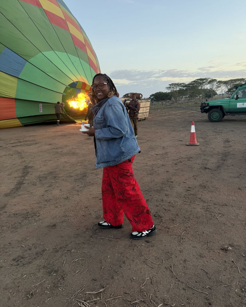 Valicia beside a hot air balloon inflating at dawn on the savanna